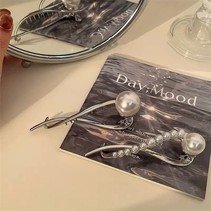 Elegante zilveren haarklemmen in cijfer acht vorm met parels op een dienblad