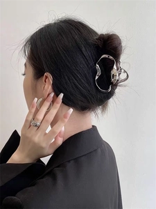 Detailed view of silver liquid metal hair claw clip in irregular geometric hollow design