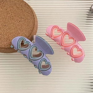 Gros plan sur les pinces à cheveux en acétate avec cœurs évidés rose et lavande