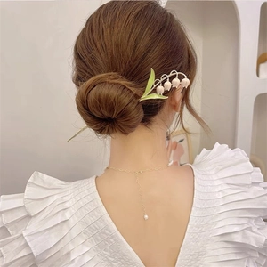 Épingle à cheveux élégante muguet portée sur un chignon bas vue arrière pour femme