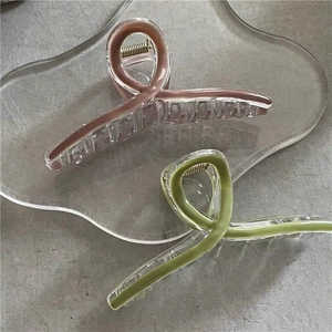 Detail of pink and green hair claws on a transparent tray over a textured stone surface