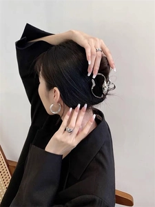 Close-up of geometric silver shark hair clip and rings on model in minimalist style