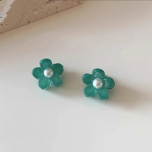 Dettaglio di due mollette a fiori color verde acqua con perle su uno sfondo di pietra