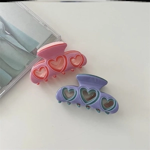 Détail de pinces à cheveux en forme de cœur rose et violet en plaque d'acétate