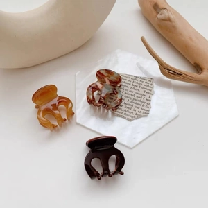 Three-piece mini resin hair claw set with amber, marble, and coffee patterns on display