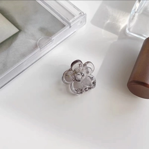 Close-up of a small translucent smoky grey flower hair claw with a visible metal spring