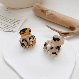 Detailed view of two mini tortoise shell hair claws in amber and cream patterns