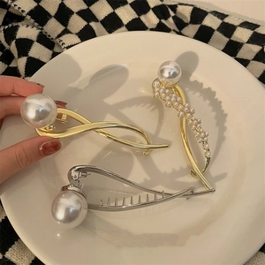 Detailweergave van elegante parelbanaanklemmen in goud en zilver op een dienblad