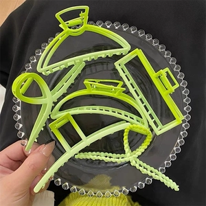 Macro detail of various lime green matte geometric hair claws in a glass bowl