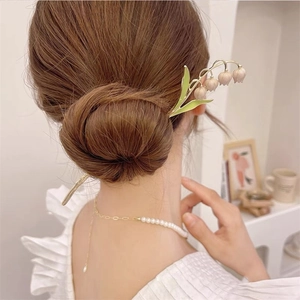 Détail d'un pic à cheveux muguet élégant avec feuilles vertes et métal doré raffiné