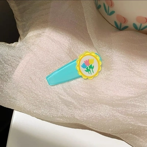 Detail of a blue tulip hairpin with yellow wavy disc on soft white fabric background