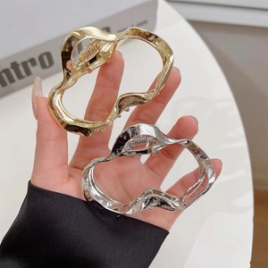 Detailed view of irregular wavy geometric metal hair claws in glossy gold and silver finish