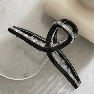 Close-up of minimalist black and clear acrylic hair claw clip with cross knot design