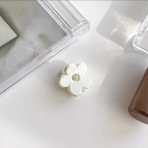 Detailed close-up of a mini cream-colored floral resin hair claw clip in a minimalist setting