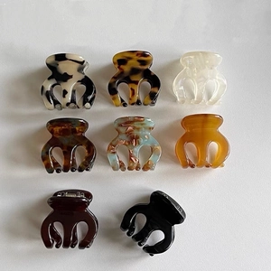 Flat lay of small acetate hair claw clips in marble, tortoiseshell and solid colors