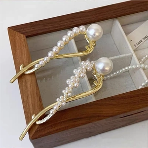 Detailopname van elegante gouden haarklemmen met witte parels op een houten sieradendoos