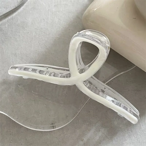 Macro detail of elegant clear shark hair claw with white minimalist drip oil swirl patterns