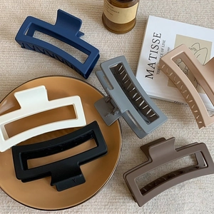 Detailed arrangement of 12cm matte hair claw clips in various colors on a ceramic tray