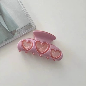 Gros plan sur une pince à cheveux rose en acétate avec trois motifs de cœurs évidés