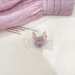 Detailed macro view of purple and orange marble gradient butterfly hair clip with gold spring