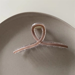 Detailed close-up of a mocha brown claw clip with a transparent finish on a grey ceramic plate