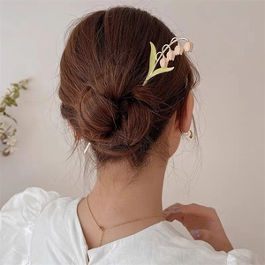 Détail d'une épingle à cheveux muguet élégante stylisée dans un chignon moderne pour femme