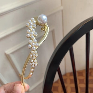 Detailopname van een gouden haarclip met bloemenparels en een grote accentparel