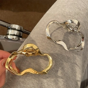 Detail of irregular wave hollow metal hair claw clips in shiny gold and silver finishes