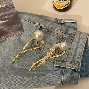 Detail van elegante gouden haarclips met witte parels op blauwe denim achtergrond