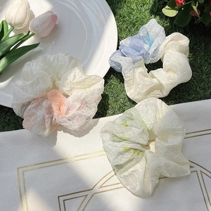 Close-up of three large pastel organza scrunchies with grid texture and wavy edges