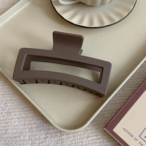 Macro detail of the matte coffee-colored rectangular hair claw on a cream dotted tray