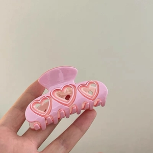 Détail de la pince à cheveux en acétate rose avec un joli design triple cœur pour femmes