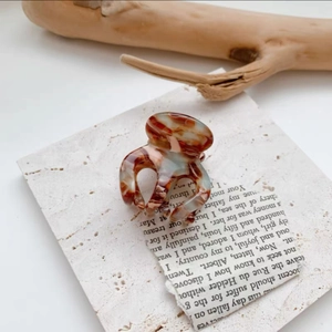 Close-up of small tortoiseshell acetate hair claw clip with marble texture on vintage paper