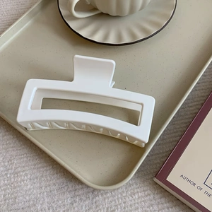 Close-up of extra large ivory matte hair claw clip for thick hair on a beige tray