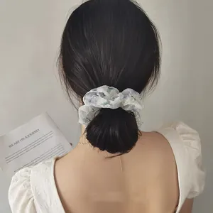 Chouchou en organza floral avec motif de fleurs bleues sur un chignon flou