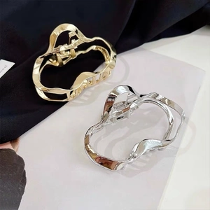 Detail of gold and silver irregular geometric metal hair claws on black silk background