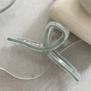 Detail of a large sage green hair claw clip with a transparent geometric design