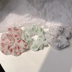 Vue détaillée de trois chouchous en organza fleuri de couleurs rouge verte et violette