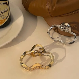 Detail view of gold and silver irregular geometric metal hair claws in a retro setting