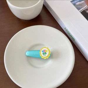 Detailed close-up of a blue tulip hair clip on a white plate with aesthetic background