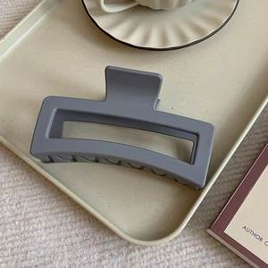 Macro shot of large matte grey rectangular shark clip on a beige ceramic tray