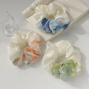 Close-up of three large mesh hair scrunchies with blue, orange, and green gradient dyes
