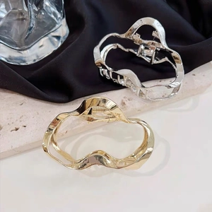 Detail showing irregular gold and silver metal hair clips with wavy geometric design