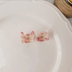 Close-up of small butterfly hair claws in pink gradient resin with marble effect