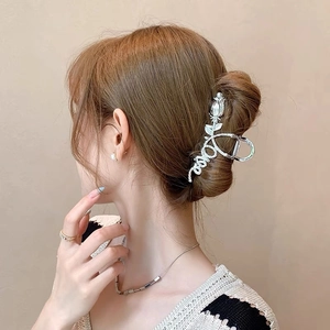 Detail view of silver rose metal hair claw with love engraving used in a hair bun