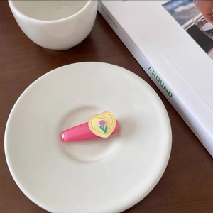 Detailed shot of pink hair clip with yellow heart and tulip pattern on wooden desk