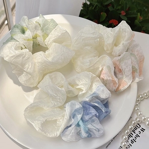 Detail of four assorted organza mesh scrunchies with plaid patterns and watercolor colors