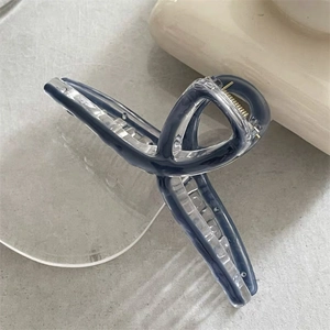 Close-up of a large shark hair claw clip with dark grey marble pattern on acrylic surface
