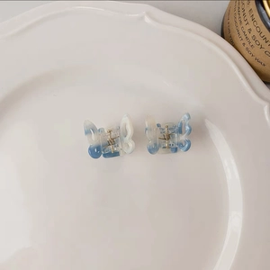 Detail of two mini blue gradient butterfly hair claws in a decorative white dish