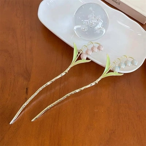 Détail des épingles à cheveux muguet en rose et bleu sur une table en bois